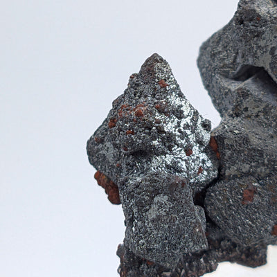 Close-up of small hematite octahedron beside larger skeletal crystal