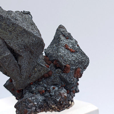 Close-up of textured octahedral hematite crystal face with reddish spots