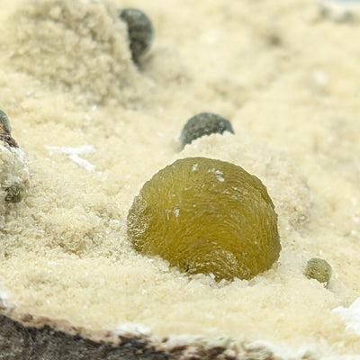 Close-up of striated Gyrolite sphere among smaller satellite spheres, Pune, India