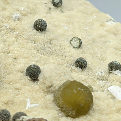 Dark satellite balls and Gyrolite sphere on textured zeolite matrix, Pune, India