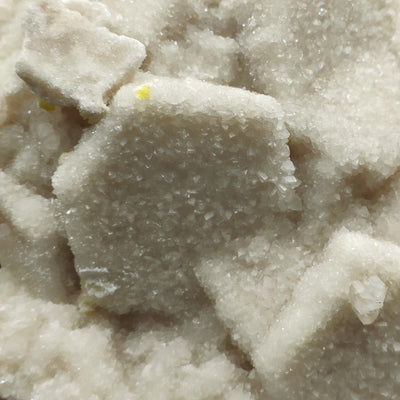 Close-up of hexagonal aragonite crystal face with tiny yellow sulfur spot