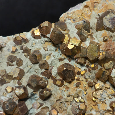 Golden pyrite crystals with iridescent surface sheen on matrix from Elba Island