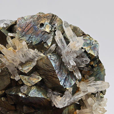 Striated arsenopyrite crystal faces with blue flash alongside clear quartz points