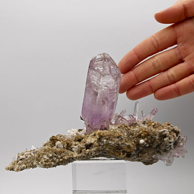 Hand holding amethyst specimen showing elongated matrix base, Veracruz, Mexico