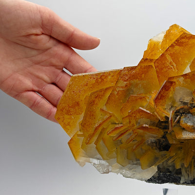 Hand holding edge of large Calcite cluster showing hexagonal crystal terminations