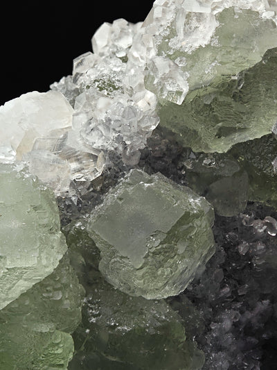 Detail of cuboctahedral green Fluorite crystal beside colorless Calcite crystals