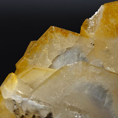 Detail of stepped hexagonal calcite crystal faces showing orange coloration