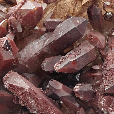 Close-up of red quartz crystal points with sandy hematite surface texture