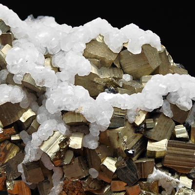 Striated pyrite crystal faces beneath draping botryoidal white calcite, Huanzala Mine, Peru