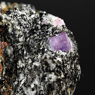 Violet Sapphire crystal on matrix edge with pink crystal in background