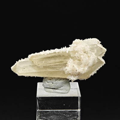 Elongated quartz crystal with calcite rim displayed on acrylic stand
