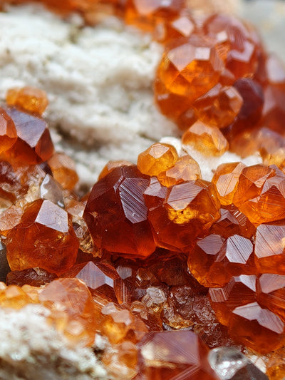 Detail of lustrous orange-red spessartine garnet crystals with striated faces
