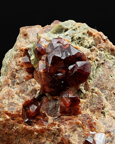 Lustrous grossular garnet crystals with striated faces on light matrix