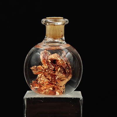 Close-up of crumpled native copper foil leaves inside glass vial
