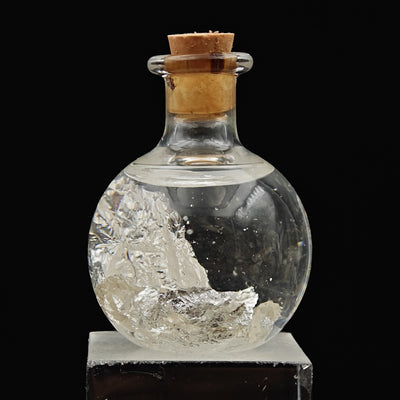 Close-up of natural silver leaf flakes inside corked glass vial